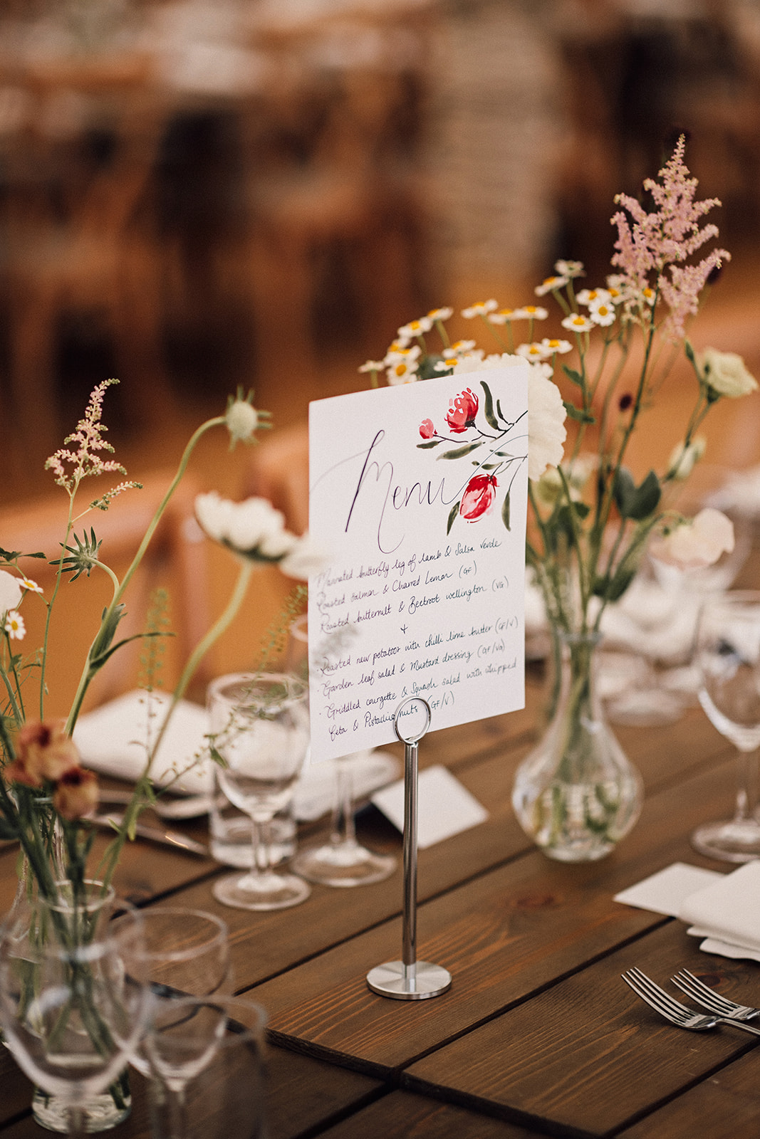 Handwritten menu card on a wooden table with wildflowers