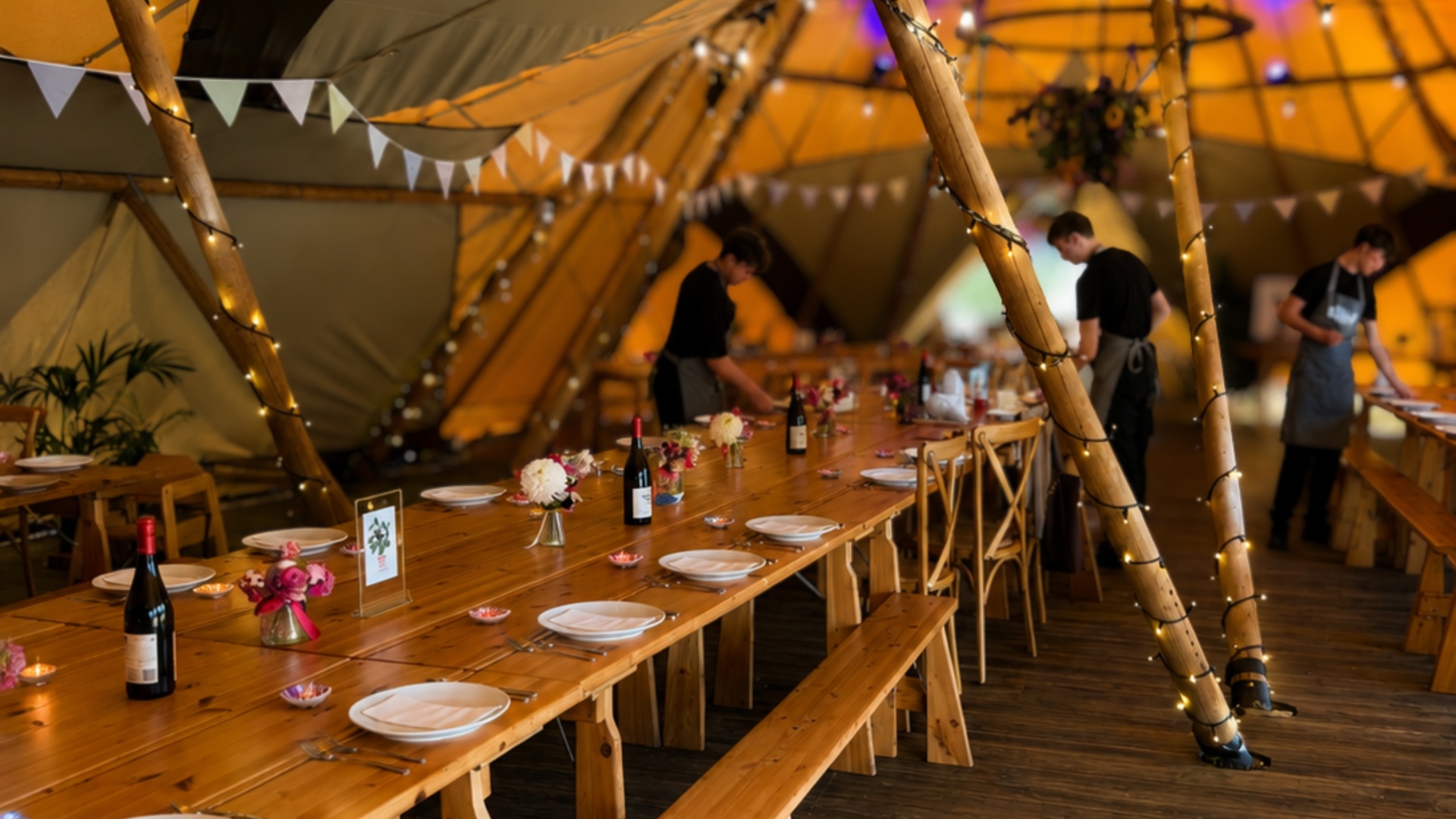 Tilia Bespoke Catering – tipi interior set for a wedding feast with warm golden light and fairy lights